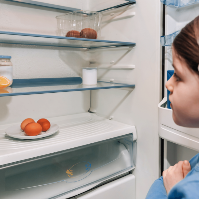 Girl looking at empty fridge due to cost-of-living-crisis